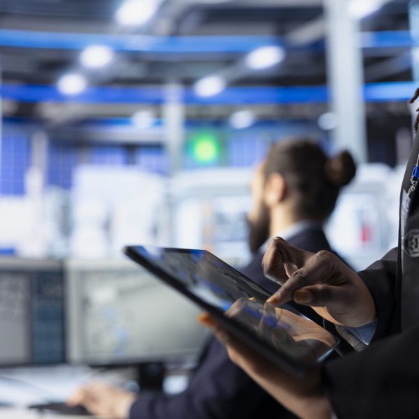 Engineer in photovoltaics factory reviewing system logs on tablet to identify operational inefficiencies. Photovoltaic plant worker adjusting manufacturing parameters on device, close up