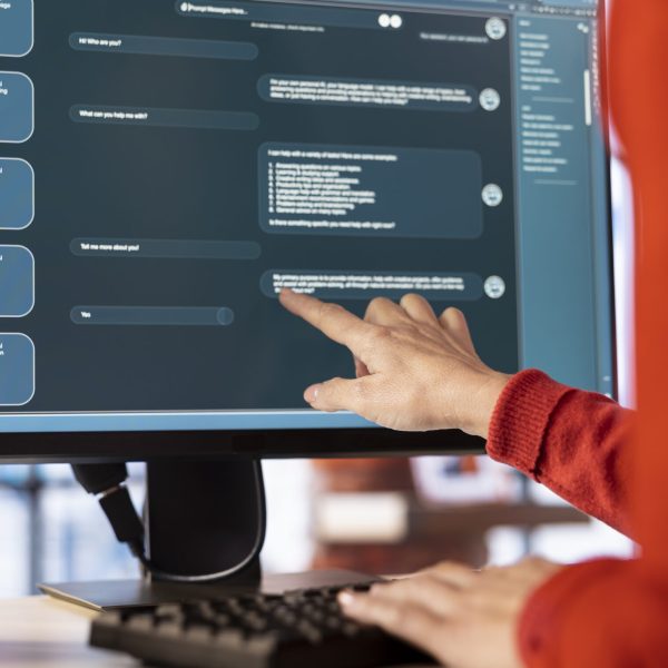 Woman uses AI chatbot system on a computer to guide her through problem solving tasks, futuristic technology highlights smart algorithms and machine learning. Online communication and support.